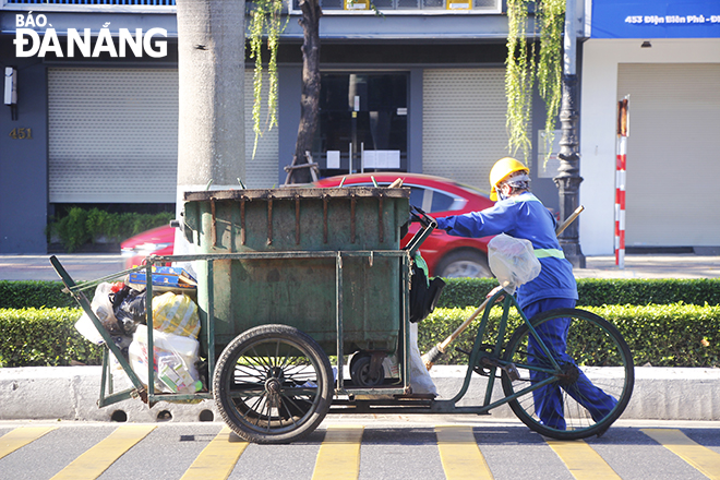 A male sanitation worker picking up garbage on Dien Bien Phu Street. Photo: XUAN DUNG