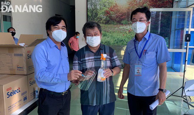 Lãnh đạo Sở Tài nguyên và Môi trường tặng kính chắn giọt bắn và nước khử khuẩn cho Công ty CP Môi trường Đô thị Đà Nẵng. Ảnh: HOÀNG HIỆP