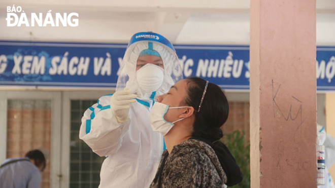 The strain of the coronavirus causing infections in Da Nang has a very fast spread rate and those who contract may come in with critical illness. A local woman living a high-risk neighborhood in Son Tra District is seem having her nasal swab samples taken for COVID-19. Photo:  PHAN CHUNG