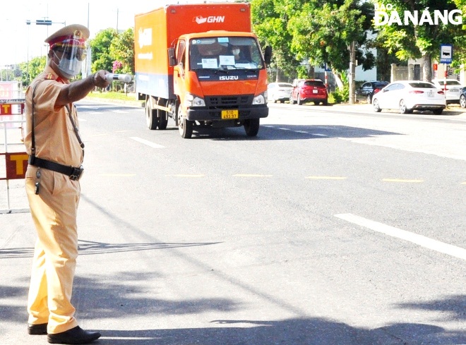 Lực lượng Cảnh sát giao thông tại điểm chốt trên tuyến đường quốc lộ 1A (xã Hòa Phước, huyện Hòa Vang) ra hiệu yêu cầu tài xế dừng phương tiện khai báo y tế và xuất trình giấy tờ theo quy định. Ảnh: LÊ HÙNG