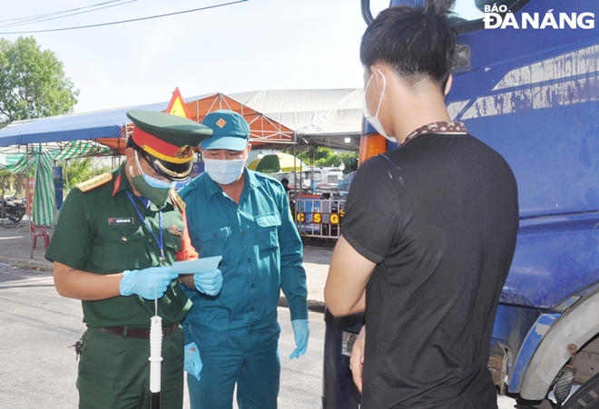 Lực lượng Cảnh sát giao thông làm nhiệm vụ tại điểm chốt trên tuyến đường quốc lộ 14B (xã Hòa Nhơn, huyện Hòa Vang) hướng dẫn tài xế chở rau củ quả của Tập đoàn Phương Trang ủng hộ Đà Nẵng dừng xe khai báo y tế. Ảnh: LÊ HÙNG