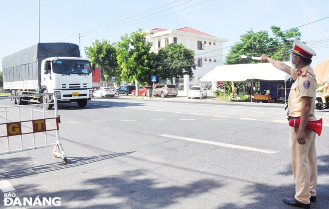 A traffic police officer pulls over a driver for check at a checkpoint located on a section of the National Highway 1A in Hoa Phuoc Commune. Photo: LE HUNG