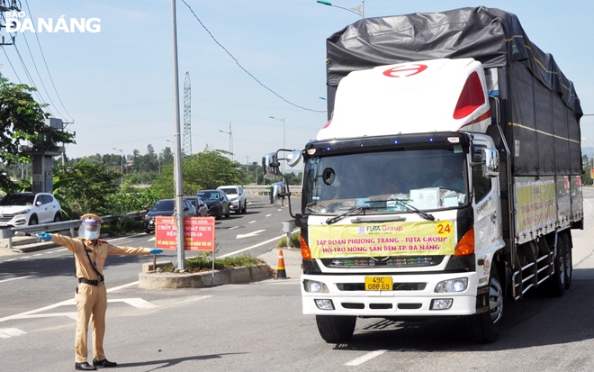  The traffic police on duty at a checkpoint on National Highway 14B in Hoa Nhon Commune, Hoa Vang District guide a truck carrying fruit and vegetables operated by the Phuong Trang Group in support of Da Nang to pass through the site. Photo: LE HUNG