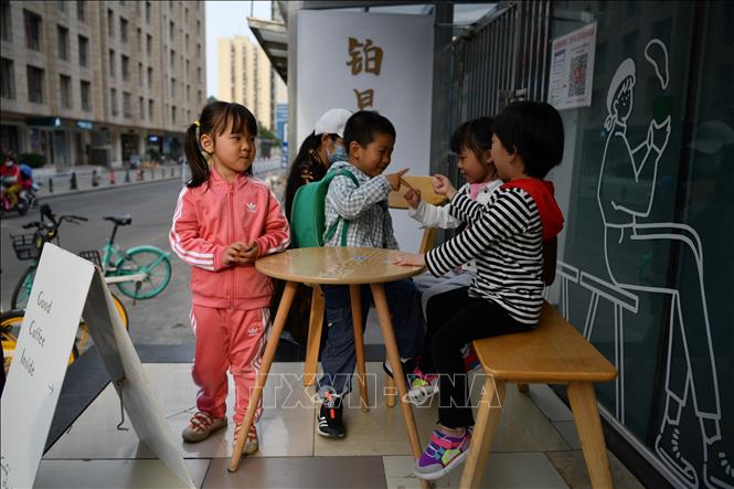 Trẻ em vui chơi bên ngoài một quán cà phê ở Bắc Kinh, Trung Quốc, ngày 11/5/2021. Ảnh: AFP/TTXVN