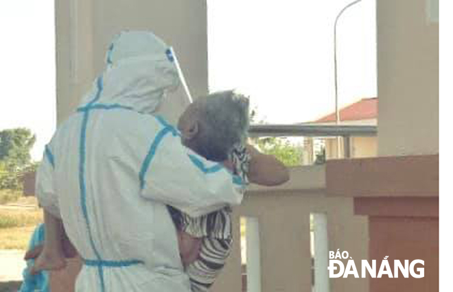 Border guard male soldier carrying an 81-year-old woman who is a COVID primary close contact in his arms from a car to the second floor of a designated quarantine facility located on Huynh Ngoc Hue Sstreet in Thanh Khe District. He also says: 