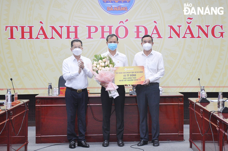 Da Nang Party Committee Secretary Nguyen Van Quang (first, left) and municipal People's Committee Chairman Le Trung Chinh (first, right) receive the symabolic board of the support from the Sun Group. Photo: LE HUNG