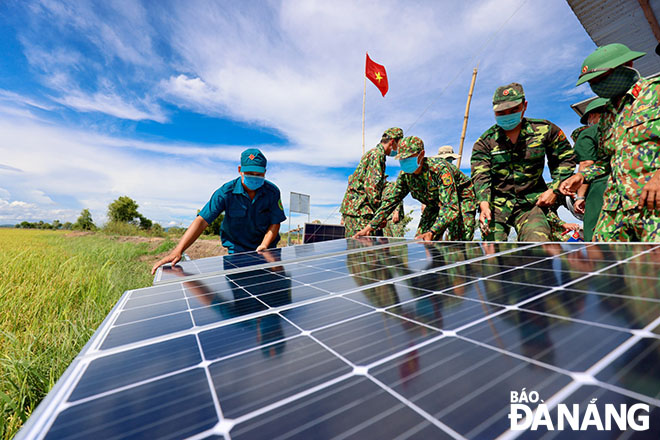 Trung úy Nguyễn Văn Dưỡng cùng đồng đội lắp tấm năng lượng mặt trời tại đơn vị để sử dụng thắp sáng vì nơi anh đóng quân không có điện. Ảnh: HỒNG QUANG