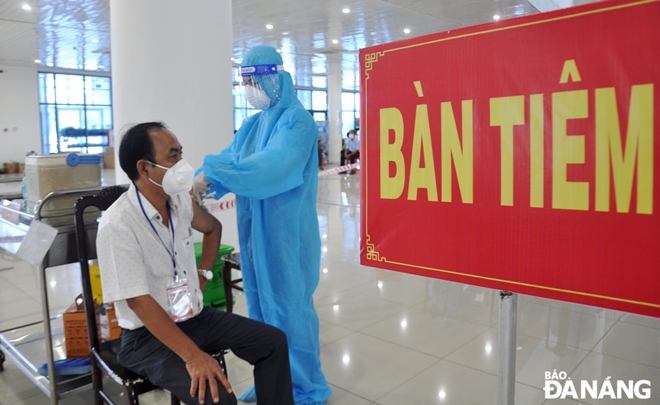 A healthcare professional in Cam Le District administering COVID-19 vaccine for an eligible man. Photo: LE HUNG