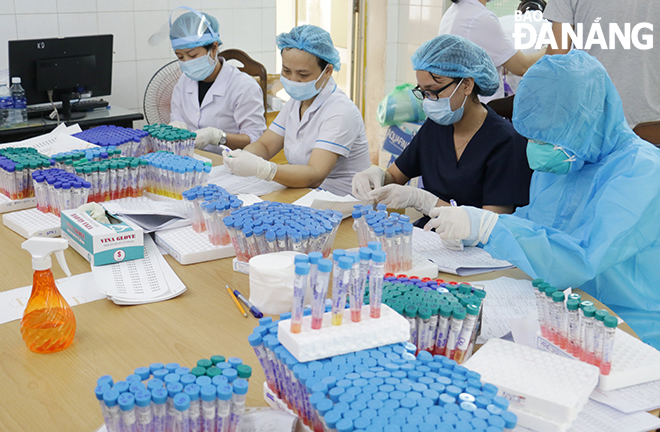 Each pooled sample tube is carefully handled by the CDC medical staff. Photo: LE HUNG