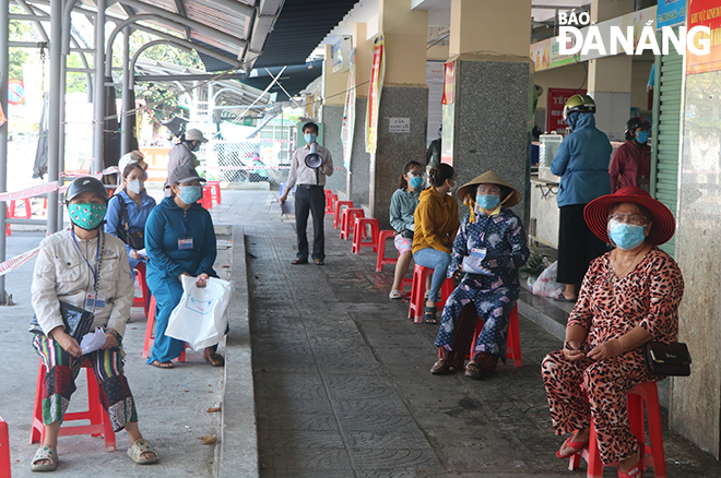  Shoppers must stand in line to wait for their turns to enter the market. Photo: VAN HOANG