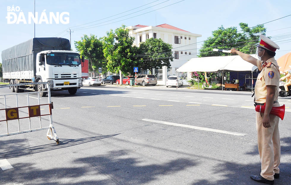 A police officer at the checkpoint on National Highway 1A in Hoa Phuoc Commune, Hoa Vang District pulling over a driver to require him to declare his health status. The taskforce at COVID-19 checkpoints across the city are working around the clock.