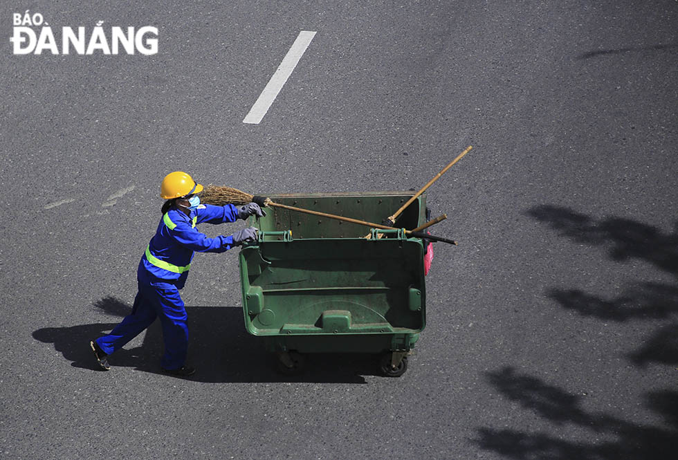 A female sanitation worker quietly does her job to keep streets clean