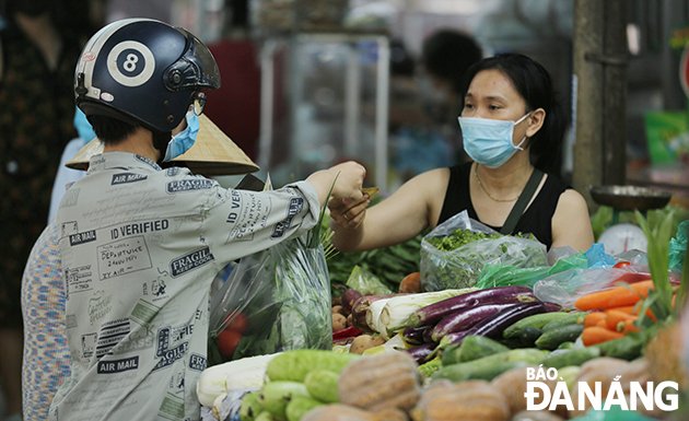 Đeo khẩu trang và giữ khoảng cách trong khi mua bán hàng hóa giúp giảm khả năng lây lan dịch bệnh. Ảnh: PHÚC AN