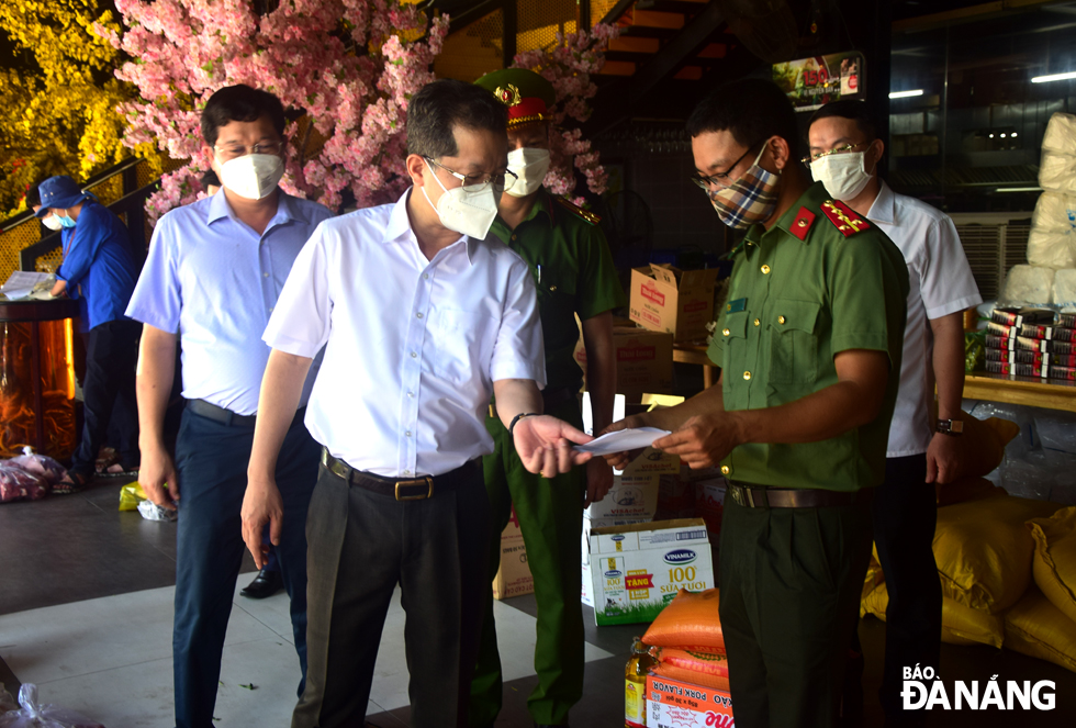 Da Nang Party Committee Secretary Nguyen Van Quang (centre) extends words of  encouragement to local police officers and men who are on duty at a mobile sales point. Photo: TRONG HUY