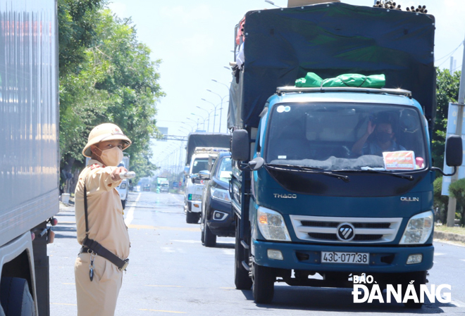 A local traffic officer pulls over a vehicle for the deployment of a rapid antigen COVID-19 test for the driver at the city’s southern gateway. Photo: NGOC PHU