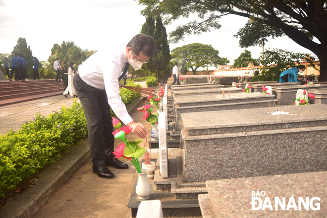 Secretary Quang burning incense at martyrs’ graves in the city’s Martyrs Cemetery. Photo: TRONG HUY