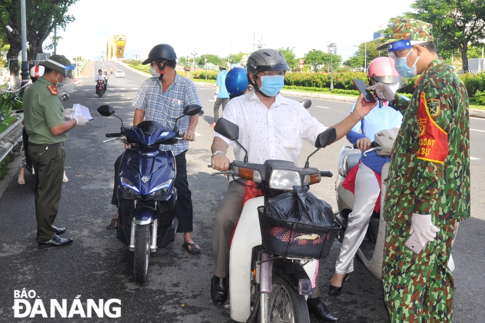 Military officers and men checking travel permits of road users when they pass through the checkpoint located on Vo Van Kiet Street in Son Tra District