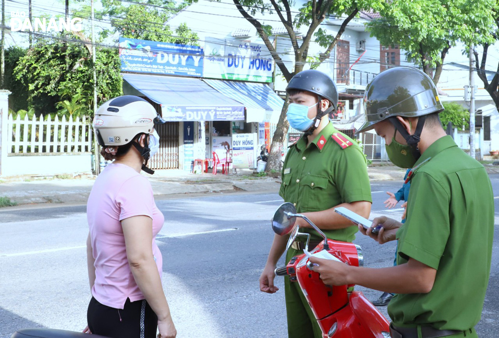 Police officers checking travel permit of a road user in the green zone in Hoa Tien Commune, Hoa Vang District. Photo: NGOC PHU