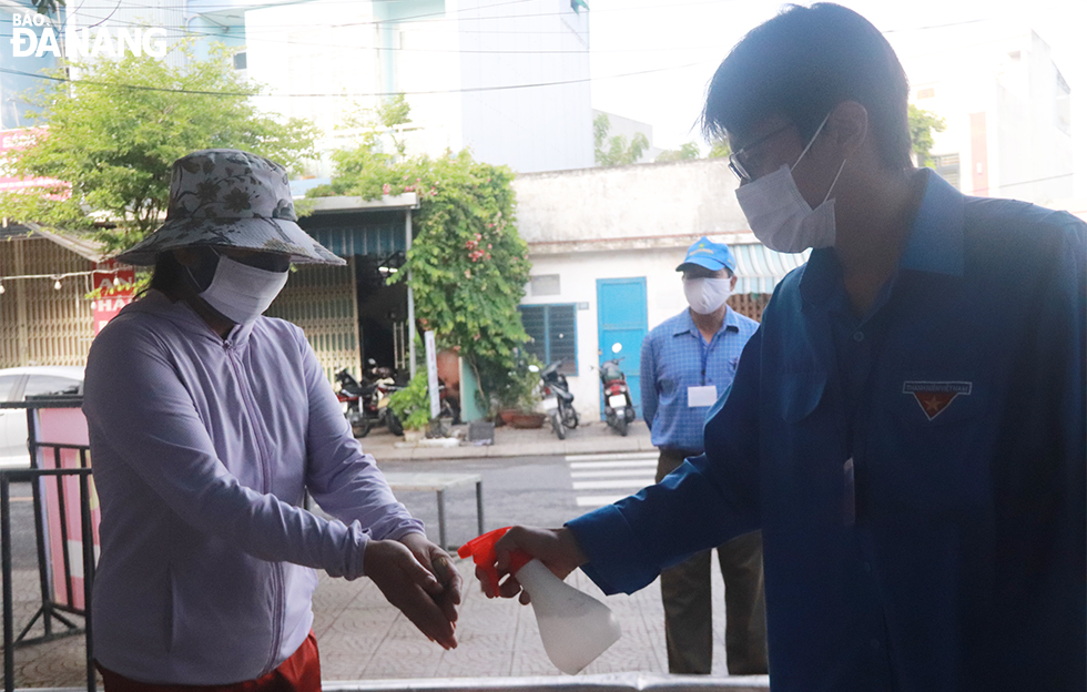 People in the green zone in An Hai Bac Ward, Son Tra District, are allowed to go food shopping in wet markets in accordance with permitted dates on their QR Code entry cards. Before entering the market, patrons are required to have their body temperature checked and disinfect their hands. Photo: DAC MANH