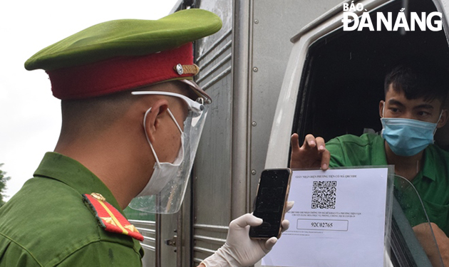 Police officers at the checkpoint on Nguyen Phuoc Lan Street in Hoa Xuan Ward, Cam Le District pulling over a vehicle driver to check his QR Code travel permit. Photo: HOANG HIEP