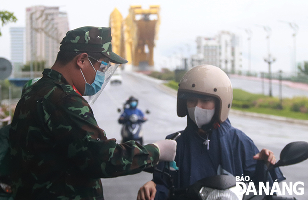 The taskforce at the checkpoint in the eastern end of the Dragon Bridge in Son Tra district checking travel permit of passers. Photo: DAC MANH