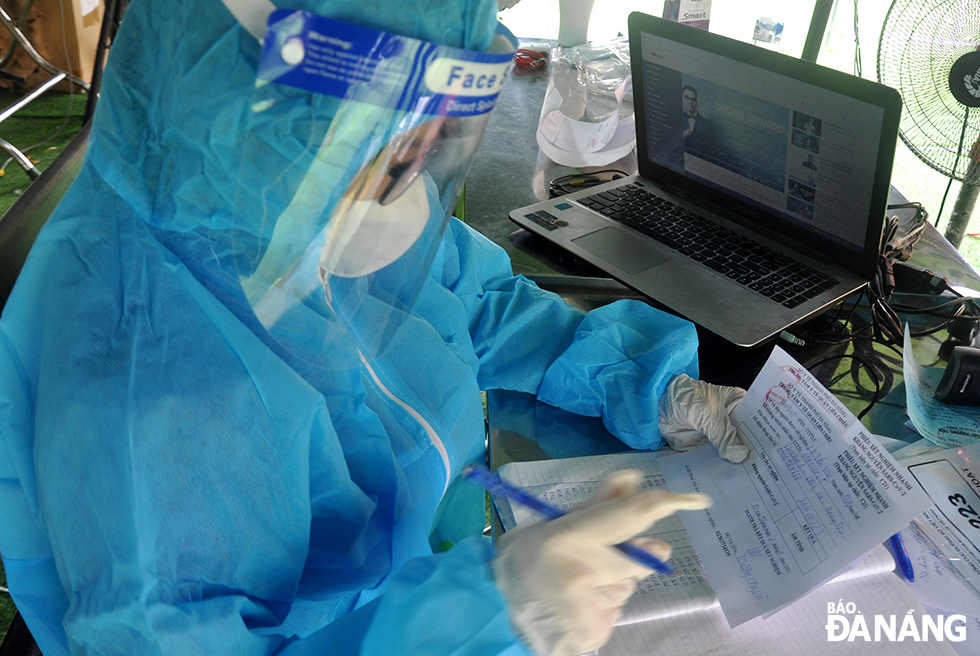 Nhân viên y tế làm nhiệm vụ tại điểm chốt cửa ngõ trên tuyến đường Tạ Quang Bửu (quận Liên Chiểu) kiểm tra kết quả test nhanh đối với tài xế.
