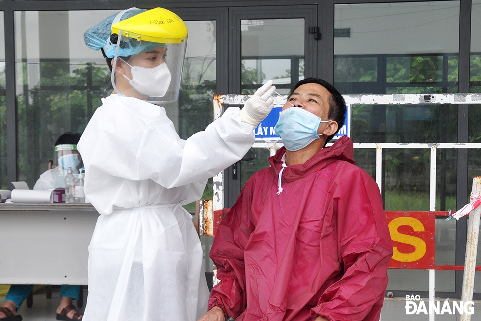  A medical staffer on duty at a checkpoint on Tran Dai Nghia Street, Ngu Hanh Son district take samples from a driver for rapid antigen testing.