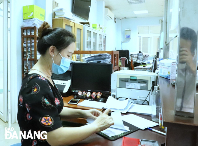 A female staff member of the One-Stop-Shop in Hoa An Ward, Cam Le District stampping on travel permits to issue them to urgent cases. Photo: NGOC PHU