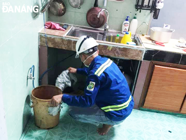 Công nhân Công ty CP Môi trường Đô thị Đà Nẵng hỗ trợ thông cống cho gia đình anh Đậu Xuân Trung. (Ảnh do nhân vật cung cấp)