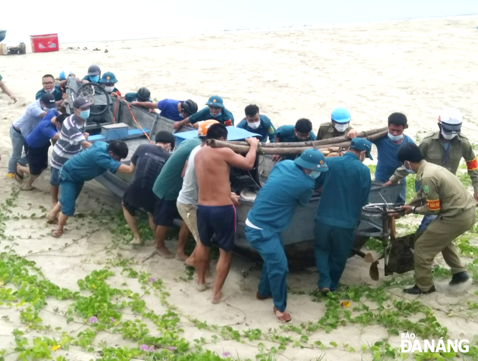 Military personnel and militia helping local residents pull a boat ashore