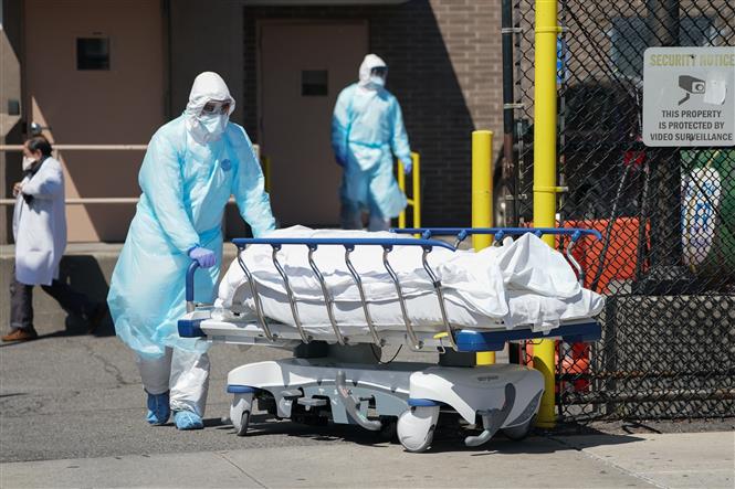 Nhân viên y tế chuyển bệnh nhân tử vong do COVID-19 tới nhà xác bệnh viện ở New York, Mỹ. Ảnh: AFP/TTXVN