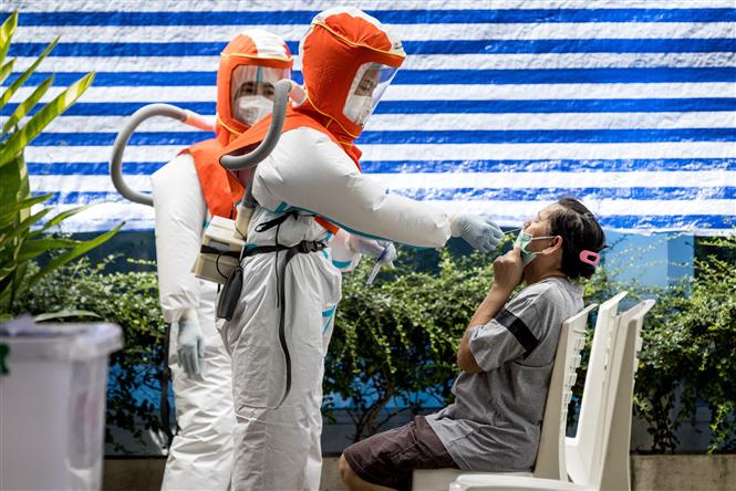 Nhân viên y tế trong trang phục bảo hộ lấy mẫu xét nghiệm COVID-19 cho người dân tại Bangkok, Thái Lan. Ảnh: AFP/TTXVN