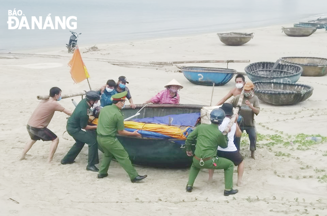 Các lực lượng chức năng giúp ngư dân phường Thọ Quang, quận Sơn Trà đưa thuyền nhỏ lên bờ trú bão. Ảnh: HOÀNG HIỆP	