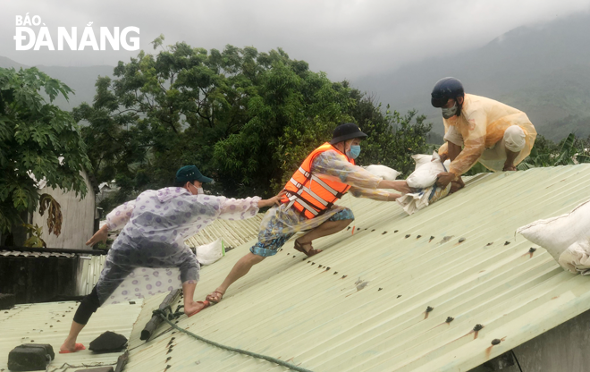 Lực lượng chức năng giúp người dân ở phường Hòa Hiệp Bắc, quận Liên Chiểu chằng chống mái tôn chuẩn bị đón bão. Ảnh: HOÀNG HIỆP
