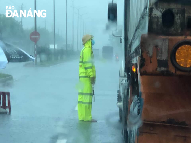 Dù mưa như trút nước kèm gió mạnh nhưng Cảnh sát giao thông vẫn miệt mài dừng, kiểm tra giấy tờ phương tiện ra vào thành phố. Ảnh ANTV