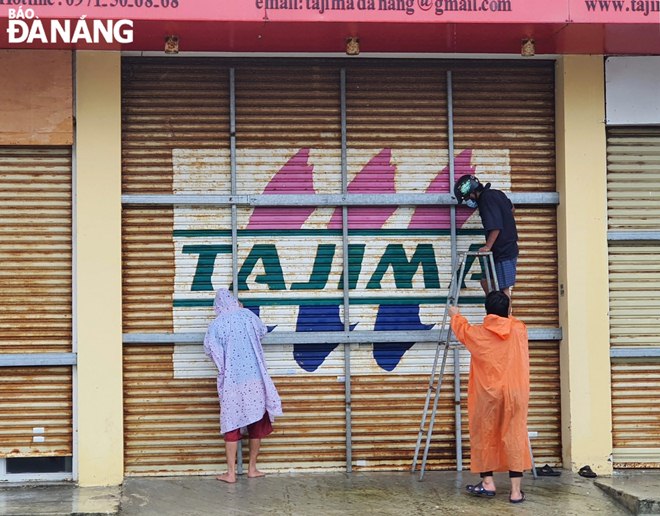 People in a shop located on Nguyen Tat Thanh Street inThanh Khe District strengthening their trading venue to weather typhoon Conson   