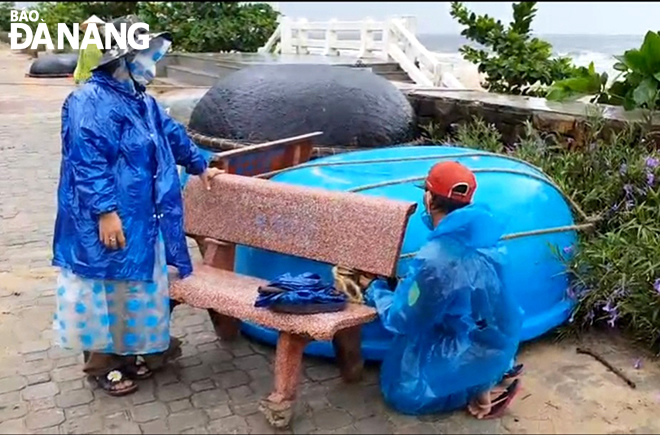 A couple tie up their boat to a stone bench to mitigate the damage to it during the storm.