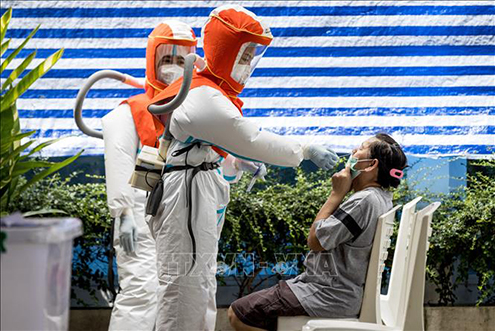Nhân viên y tế trong trang phục bảo hộ lấy mẫu xét nghiệm Covid-19 cho người dân tại Bangkok, Thái Lan. Ảnh: AFP/TTXVN