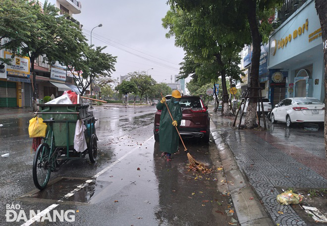 Sweeping the streets, clearing garbage and leaves on Ham Nghi Street. Photo: HOANG HIEP