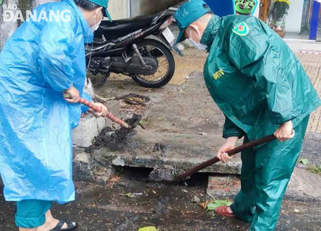 Các tổ xung kích phường Phước Ninh (quận Hải Châu) nạo vét, khơi công cửa thu nước mưa mặt đường để chống ngập úng. Ảnh: P.V