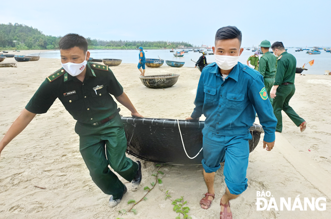 Các lực lượng chức năng giúp ngư dân phường Thọ Quang và Mân Thái (quận Sơn Trà) đưa thúng máy lên bờ trú bão.  Ảnh: HOÀNG HIỆP