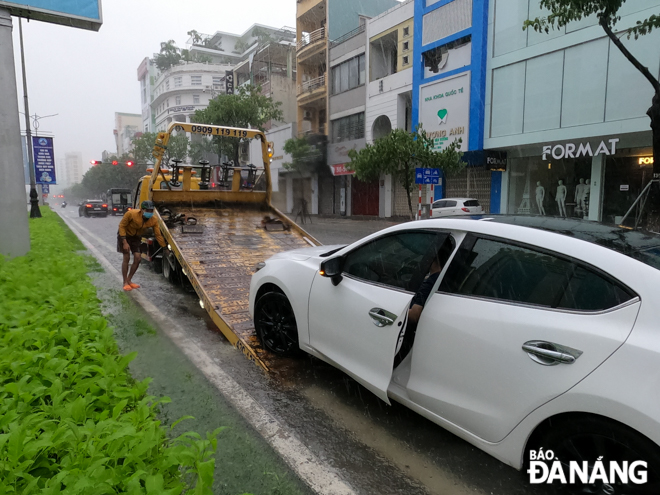 Many cars and motorbikes stalled when driving through flooded streets. In the photo: A car stalled and its driver called emergency roadside assistance. Photo: XUAN SON