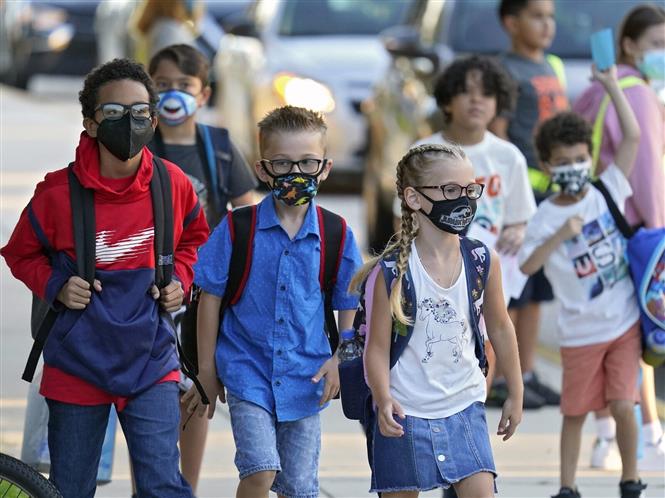 Các em nhỏ đeo khẩu trang phòng dịch COVID-19 khi ngày đầu tiên trở lại trường học sau thời gian dài giãn cách, tại Riverview, bang Florida (Mỹ) ngày 10/8/2021. Ảnh: AP/TTXVN