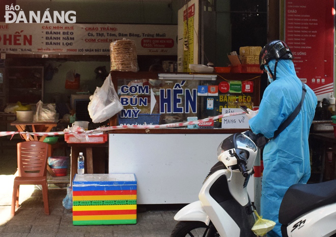 Một người giao hàng chờ mua thức ăn trước một quán ăn trên tuyến đường Huỳnh Thúc Kháng để giao cho khách. Ảnh: HOÀNG HIỆP