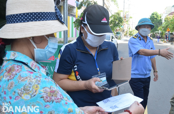  The functional force scan the QR Code available on a travel pass shown by an eligible market –goer Photo: HOANG HIEP