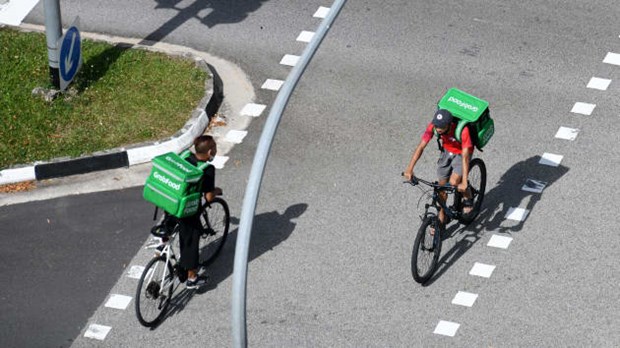 Grab delivery cyclists ride past each other in Singapore in 2020 (Photo: AFP)