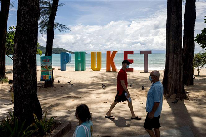 Du khách dạo chơi trên bãi biển ở Phuket, Thái Lan, ngày 14-8-2021. Ảnh: AFP/TTXVN