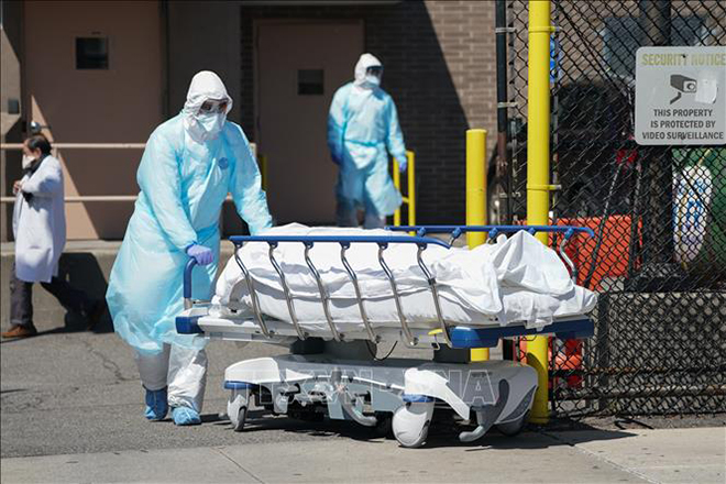 Nhân viên y tế chuyển bệnh nhân tử vong do Covid-19 tới nhà xác bệnh viện ở New York, Mỹ. Ảnh: AFP/TTXVN