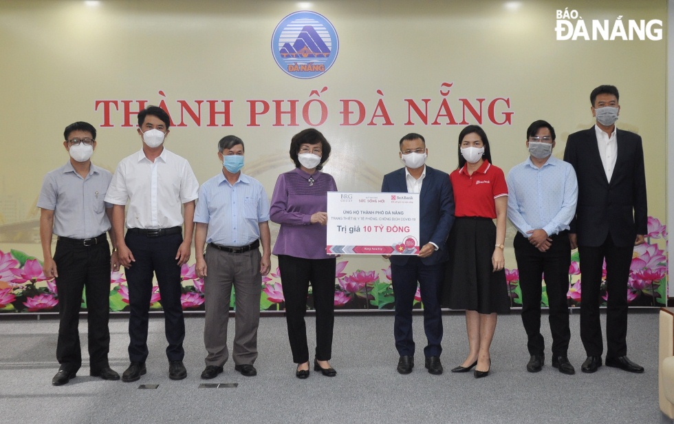 Municipal Peoples Committee Vice Chairwoman Ngo Thi Kim Yen (4th, left) receives the symbolic board of donations worth VND 10 billion from the donors. Photo: LE HUNG