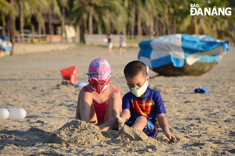 Các em nhr vui chơi tại bãi biển cũng chấp hành đúng quy định, đeo khẩu trang nơi công cộng. Ảnh: THU HÀ.